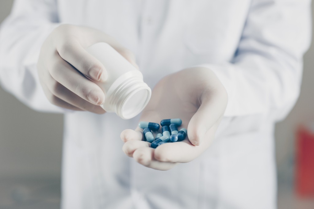 Pharmacist in gloves dispensing specialty medication capsules